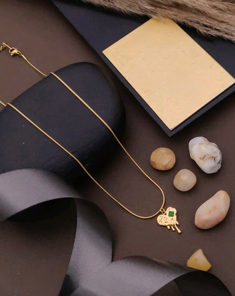 Gold necklace with a cloud pendant on a dark surface with stones