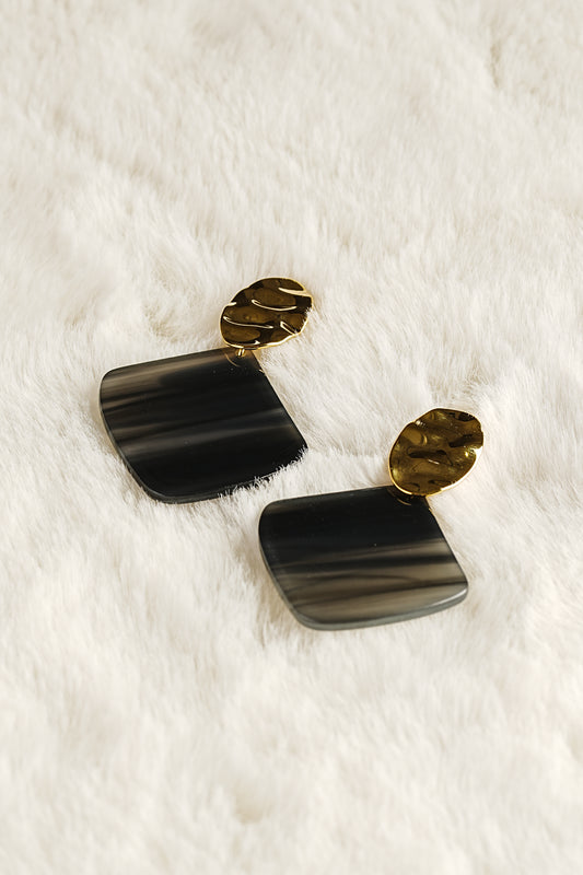 Black and gold earrings on a white fur background