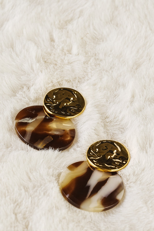Pair of tortoiseshell earrings with gold accents on a white fur background
