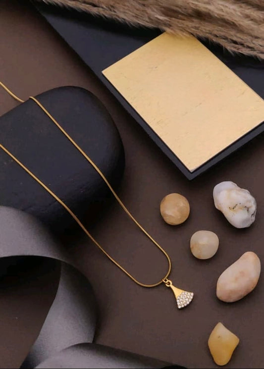 Gold necklace on a dark surface with stones