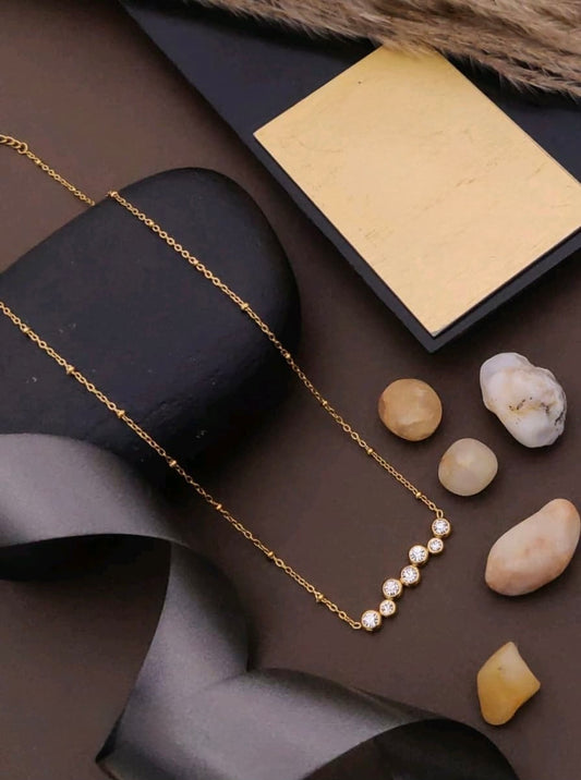 Gold necklace on a dark surface with stones